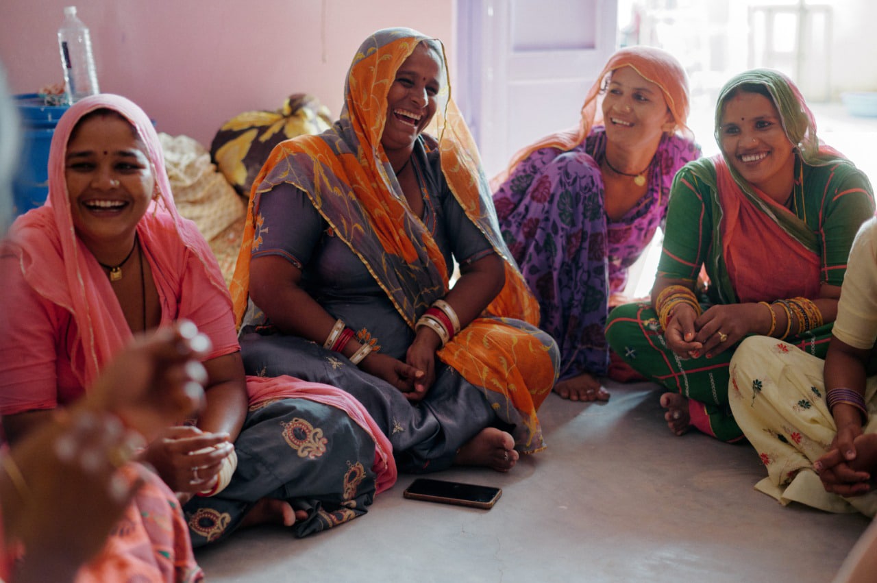 Exploitative labor practices: Image of several artisan women sitting together in a room in an Indian garment workplace.