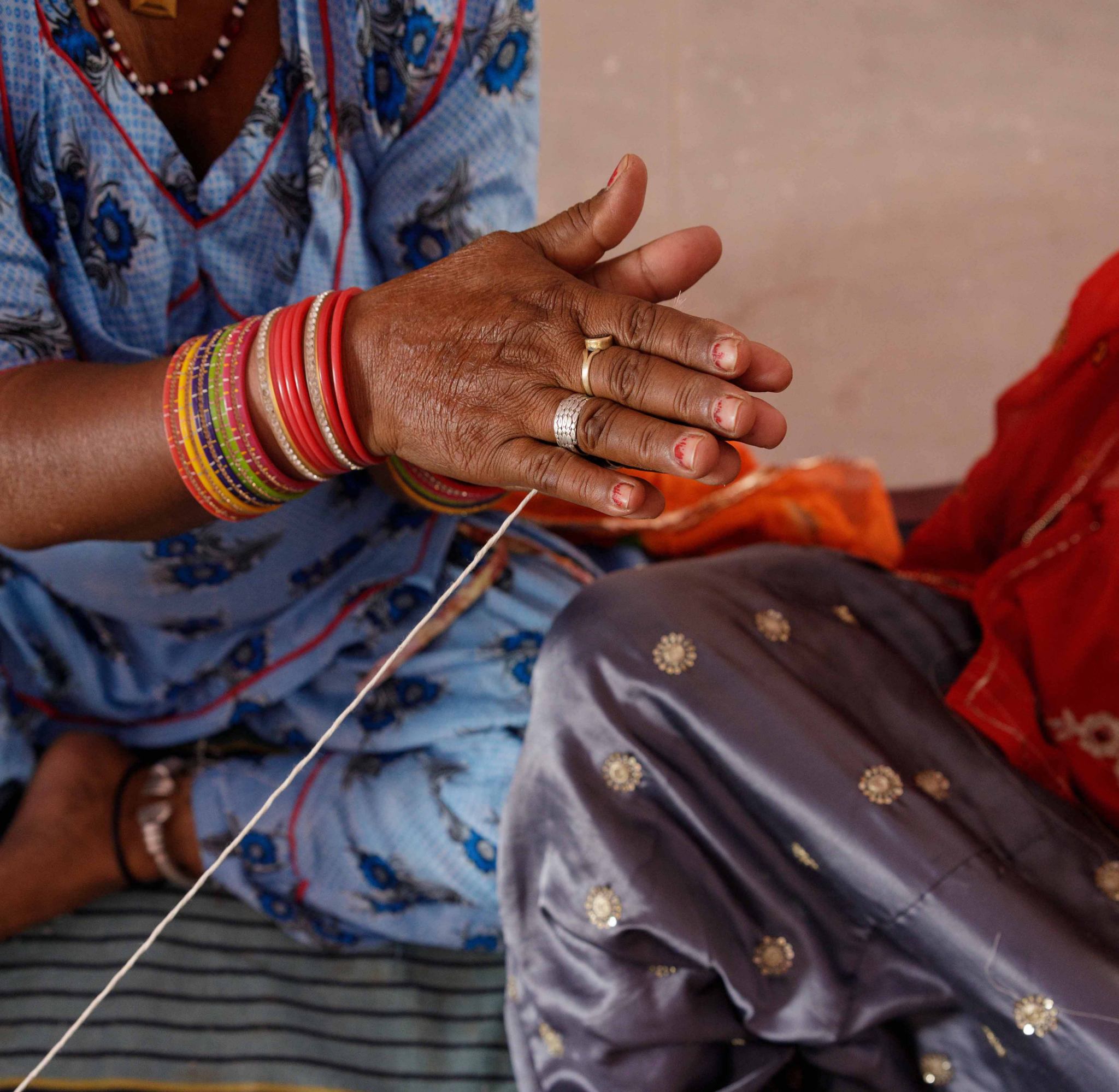 
"Saheli Women artisan skillfully threading fabric, showcasing her craftsmanship and dedication to traditional techniques."